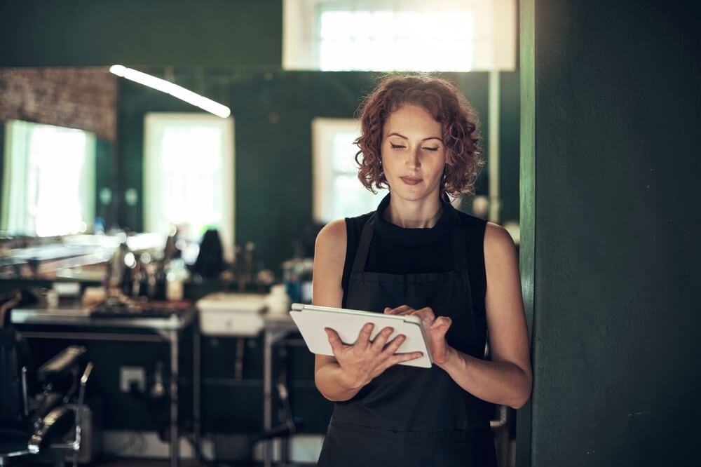 Hairdresser With Tablet In Salon For Schedule